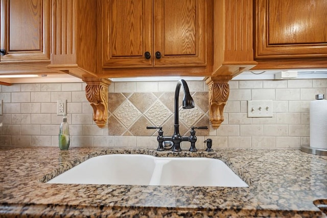 interior details featuring light stone counters, sink, and backsplash