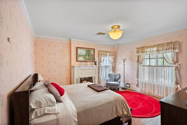 bedroom with crown molding, a fireplace, and wood-type flooring