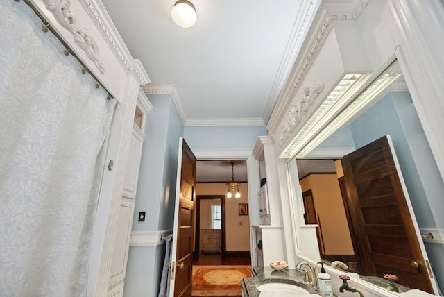 hallway with ornamental molding, wood-type flooring, and sink