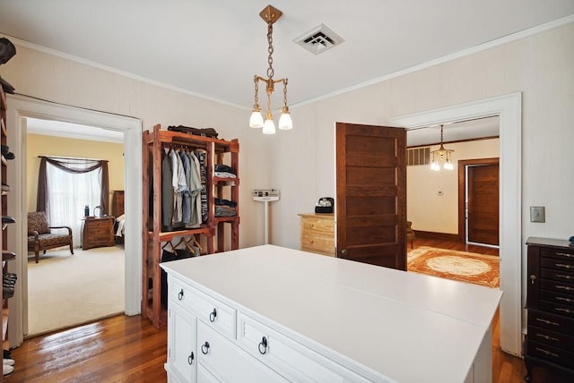 kitchen featuring a kitchen island, dark hardwood / wood-style floors, pendant lighting, white cabinets, and crown molding