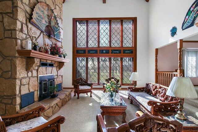 carpeted living room featuring a high ceiling, a wood stove, and a fireplace