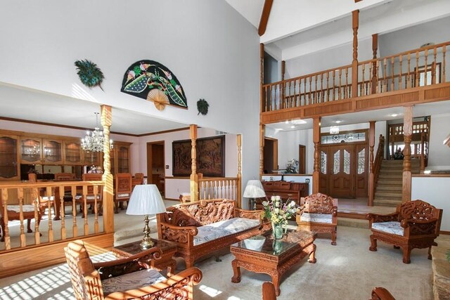 living room with high vaulted ceiling, ornamental molding, an inviting chandelier, and carpet floors