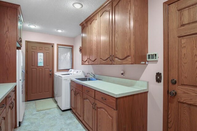 laundry room with washer and dryer, sink, cabinets, and a textured ceiling