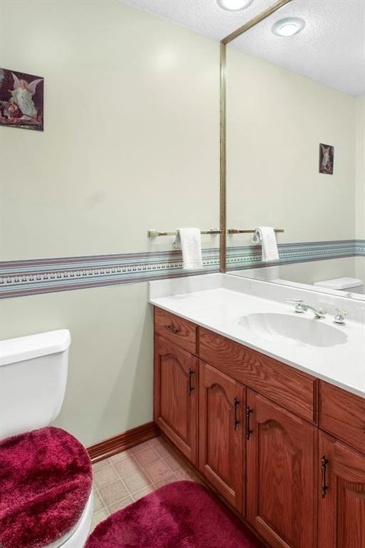 bathroom with a textured ceiling, vanity, toilet, and tile patterned floors