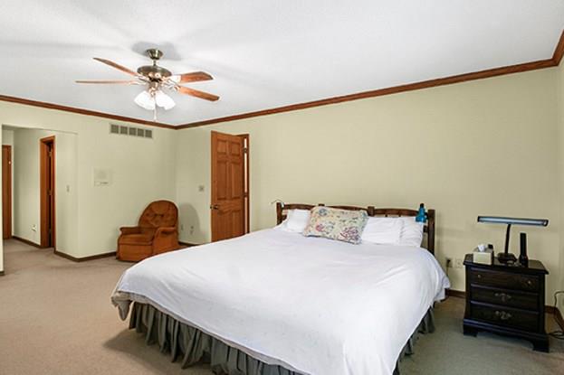 bedroom with ceiling fan, crown molding, and carpet floors