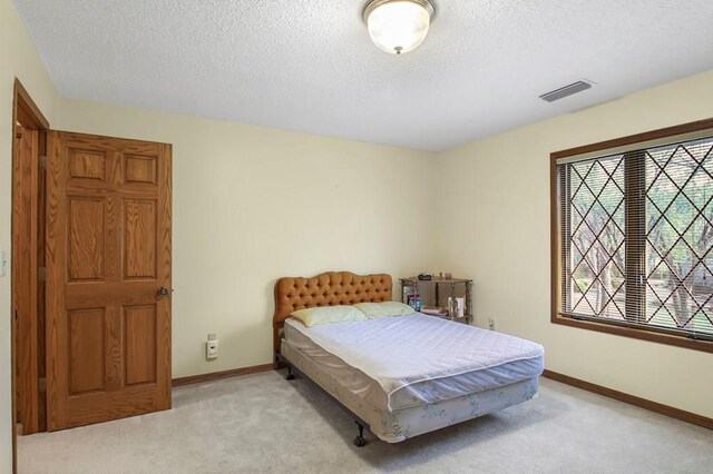 bedroom featuring a textured ceiling and light carpet