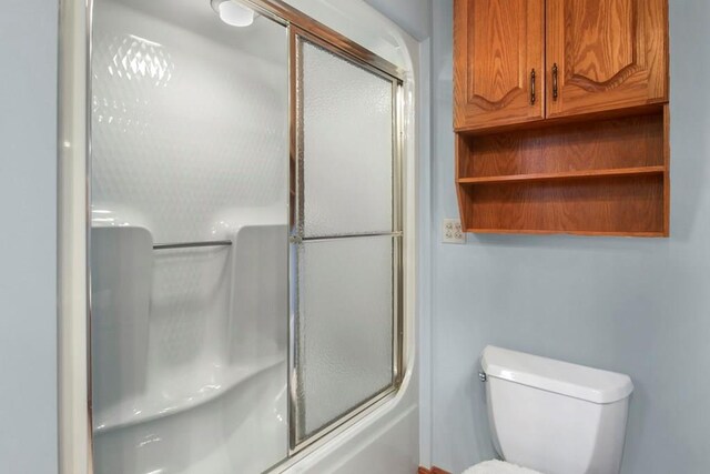 bathroom with toilet and bath / shower combo with glass door