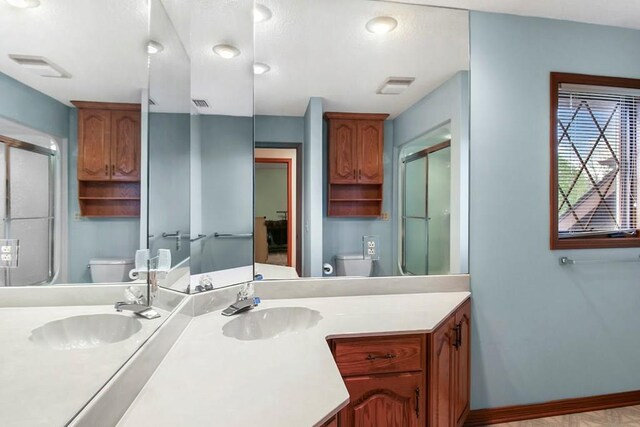 bathroom featuring vanity, toilet, and walk in shower