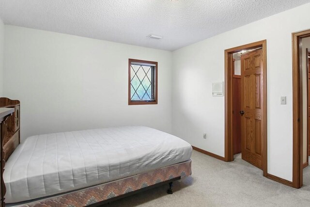 bedroom with a textured ceiling and light colored carpet