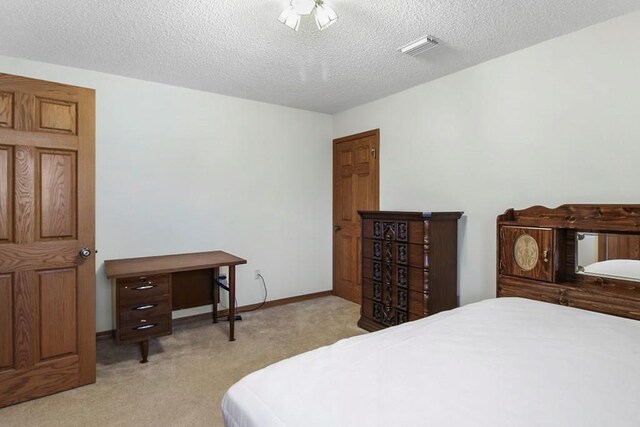 bedroom featuring a textured ceiling and light carpet