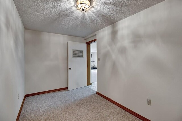 carpeted empty room featuring a textured ceiling