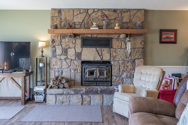 living room featuring hardwood / wood-style floors, a wood stove, a textured ceiling, and a fireplace