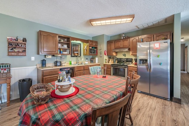 kitchen featuring appliances with stainless steel finishes, sink, a textured ceiling, and light wood-type flooring