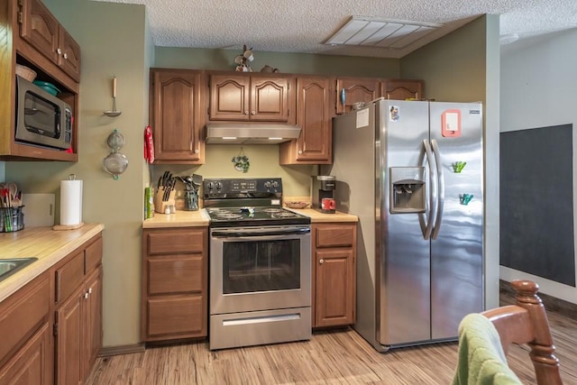 kitchen with stainless steel appliances, light hardwood / wood-style flooring, and a textured ceiling