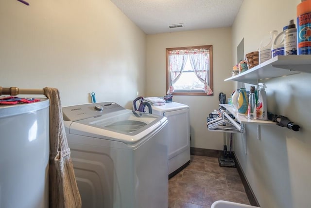 laundry area featuring dark tile flooring, washer and dryer, a textured ceiling, and water heater