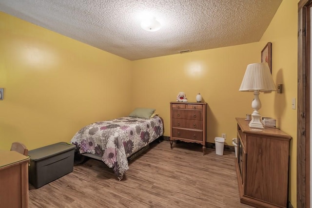 bedroom with hardwood / wood-style flooring and a textured ceiling