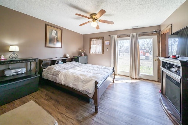 bedroom with a textured ceiling, ceiling fan, and hardwood / wood-style floors