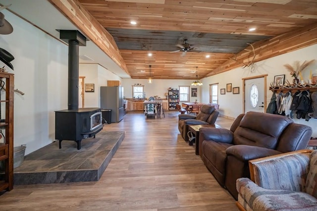 living room with wood ceiling, wood-type flooring, ceiling fan, and a wood stove