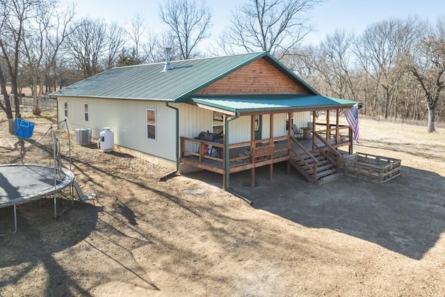 rear view of property featuring central AC unit, a trampoline, and a wooden deck