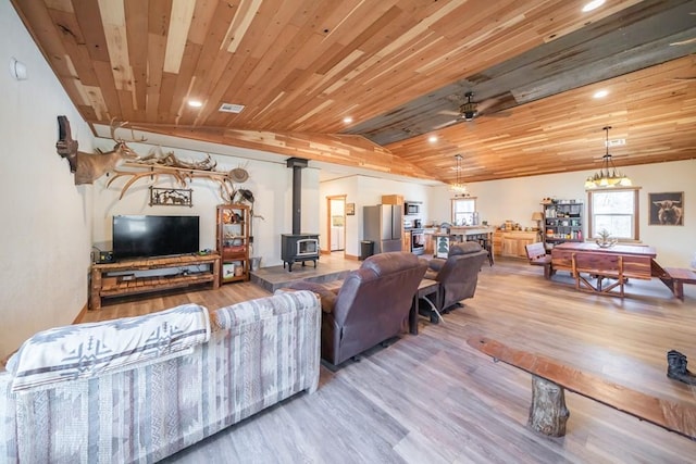 living room featuring ceiling fan, wood ceiling, lofted ceiling with beams, a wood stove, and hardwood / wood-style flooring