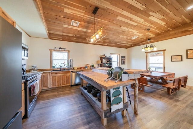 kitchen with butcher block countertops, stainless steel appliances, decorative light fixtures, dark wood-type flooring, and wooden ceiling