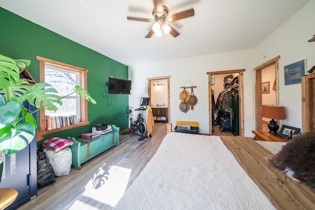 bedroom with ensuite bath, a closet, hardwood / wood-style flooring, and a walk in closet