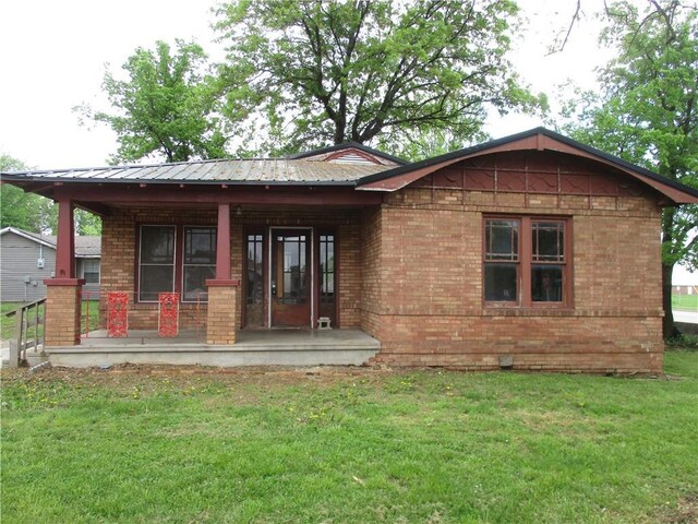 544 W Olive, Columbus, KS 66725 - rear view of house featuring covered porch, brick siding, and a yard