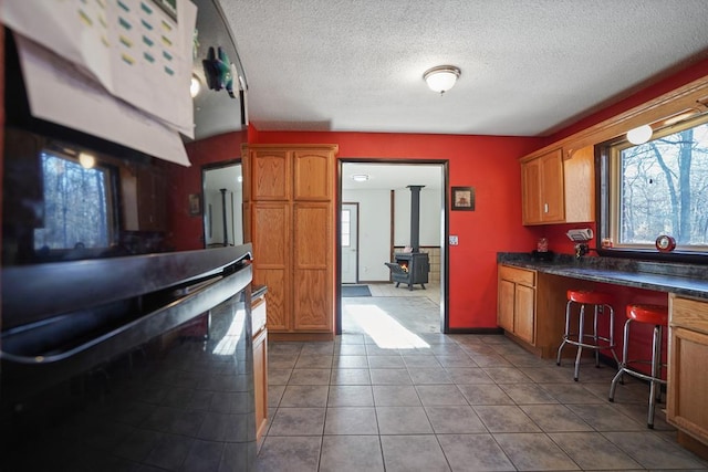 kitchen featuring light tile patterned flooring, a wood stove, and a textured ceiling