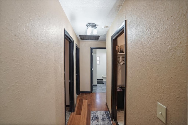 corridor featuring dark wood-type flooring and a textured ceiling