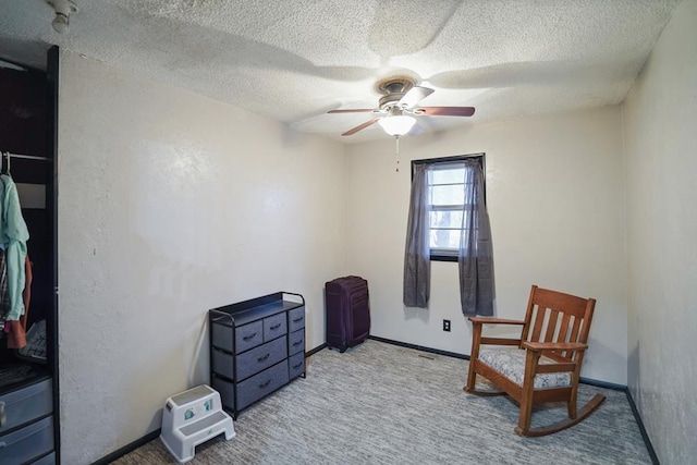 sitting room featuring light carpet, a textured ceiling, and ceiling fan