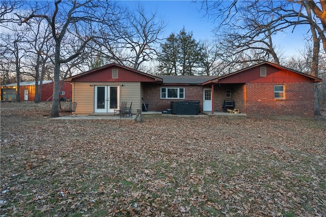 back of property featuring a patio and a hot tub