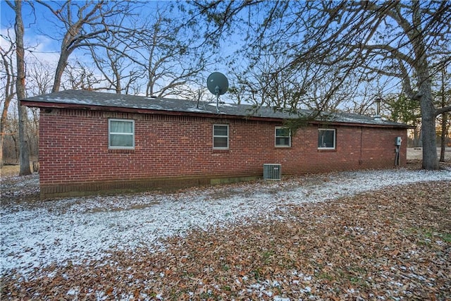 snow covered back of property with central AC