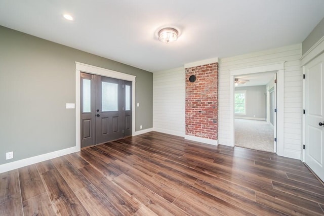 foyer with brick wall and dark hardwood / wood-style floors