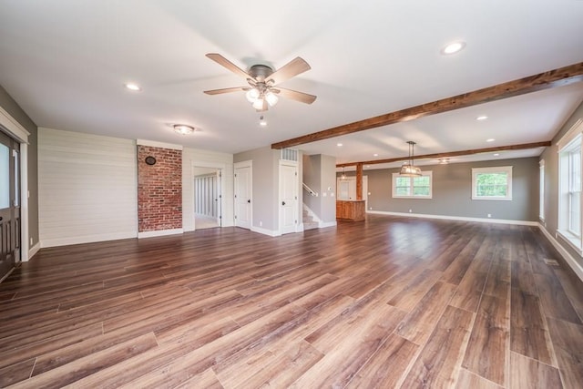 unfurnished living room with hardwood / wood-style floors, ceiling fan, beam ceiling, and brick wall