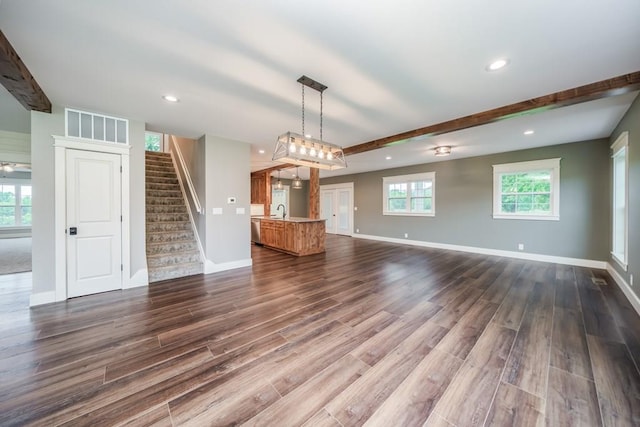 unfurnished living room featuring beam ceiling, sink, and dark hardwood / wood-style floors