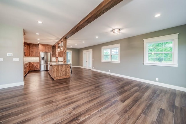 unfurnished living room with dark wood-type flooring, sink, and beam ceiling