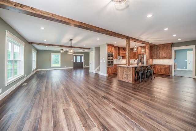 unfurnished living room with dark hardwood / wood-style floors, sink, and beam ceiling