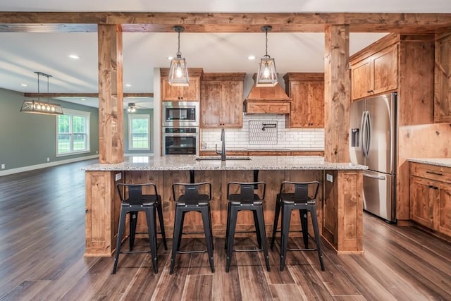 kitchen with appliances with stainless steel finishes, a breakfast bar, light stone counters, and sink