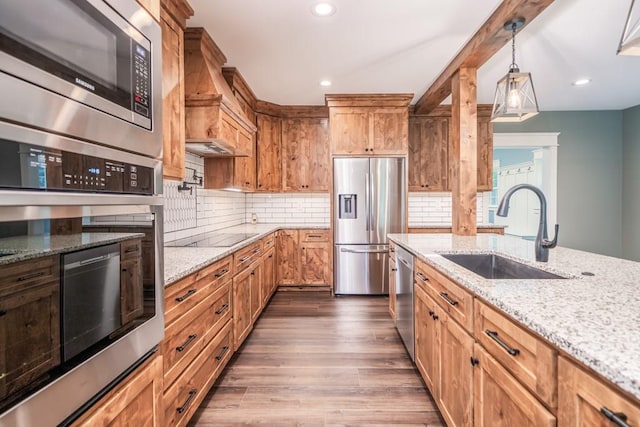 kitchen with hardwood / wood-style flooring, decorative light fixtures, custom exhaust hood, stainless steel appliances, and sink