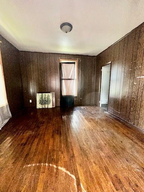 spare room with wood walls and dark wood-type flooring