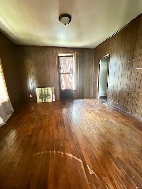 empty room with hardwood / wood-style flooring and wood walls