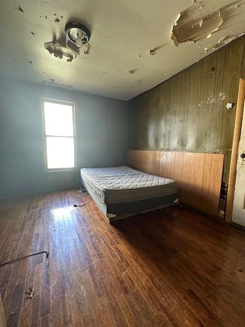 unfurnished bedroom featuring dark wood-type flooring and wooden walls