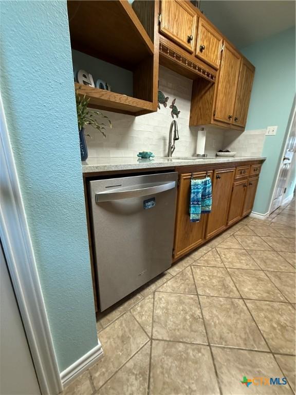 68 Silkstocking St, Port Lavaca, TX 77979 - kitchen featuring stainless steel dishwasher, a sink, light countertops, light tile patterned floors, and decorative backsplash