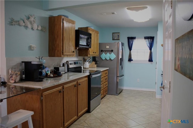 68 Silkstocking St, Port Lavaca, TX 77979 - kitchen with appliances with stainless steel finishes, light countertops, brown cabinets, light tile patterned floors, and baseboards