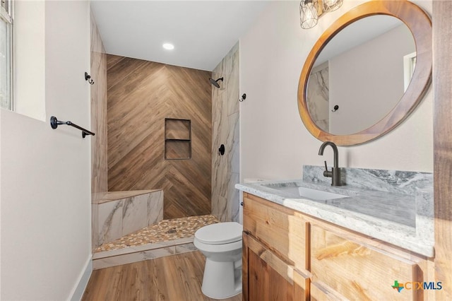 full bath with wood finished floors, vanity, toilet, recessed lighting, and tiled shower