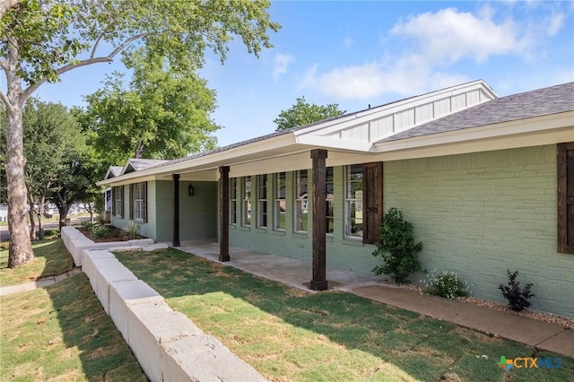 view of side of property with a yard, a patio area, and brick siding