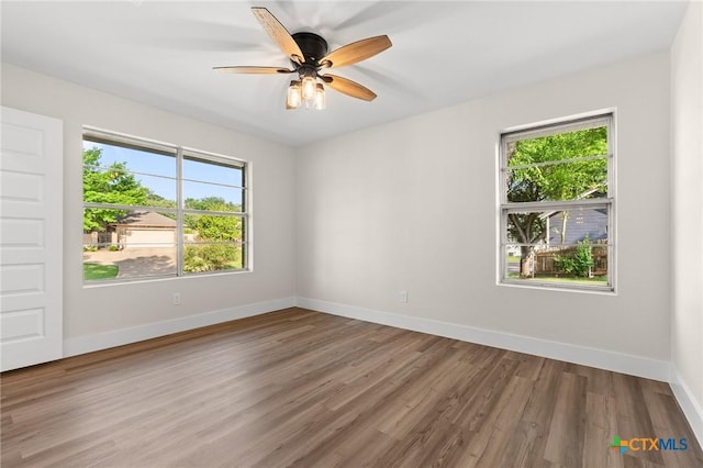 spare room with a ceiling fan, baseboards, a healthy amount of sunlight, and wood finished floors