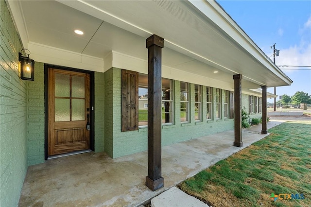 property entrance featuring a yard and brick siding