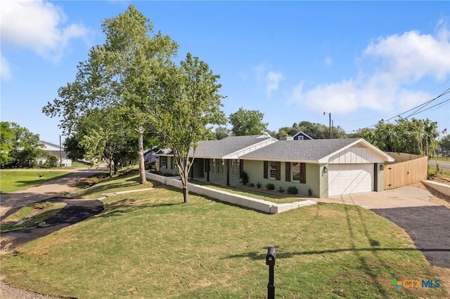 single story home with a garage, a shingled roof, a front yard, and aphalt driveway