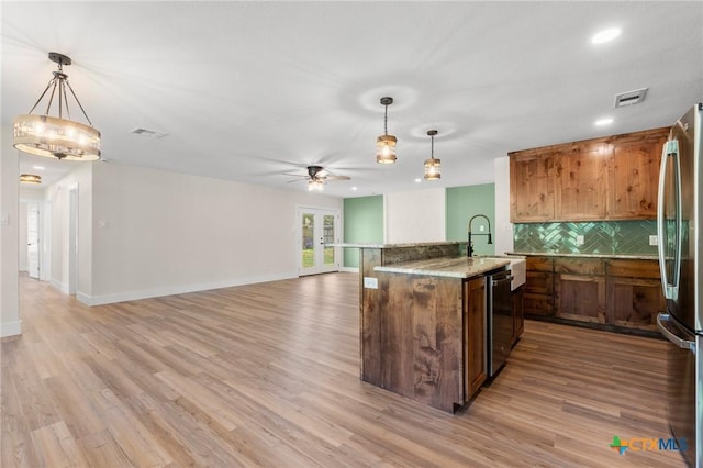 kitchen with stainless steel appliances, ceiling fan, decorative backsplash, and light wood finished floors